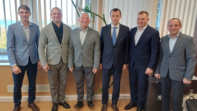 Klasiski ģērbti vīrieši, tehniskās uzraudzības pārstāvji no Latvijas un Ukrainas