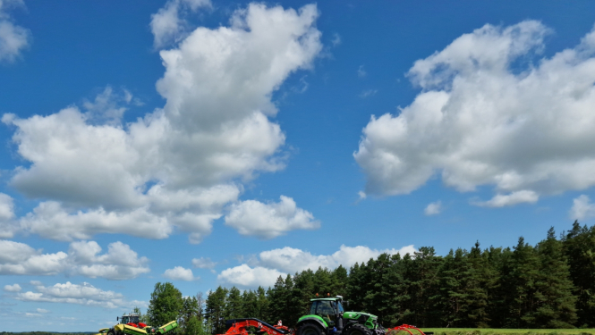 Traktortehnika uz lauka pļauj un vāc zāli, sienu