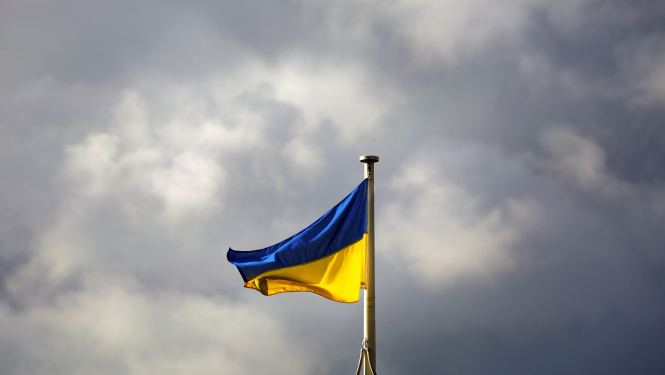 UA zili dzeltenais karogs pret mākoņainām debesīm