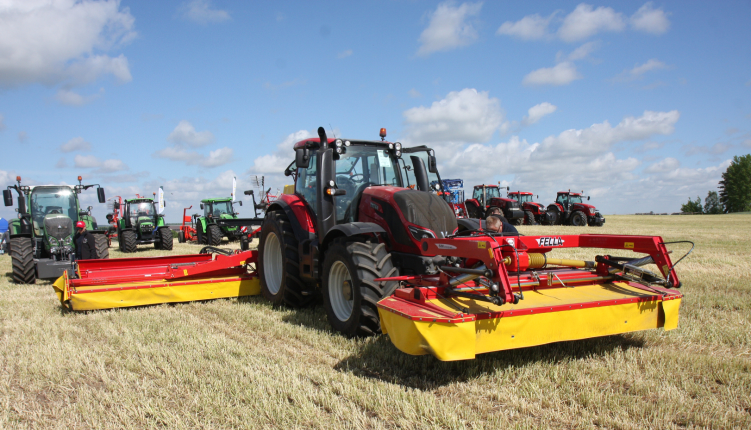 Krāsaini traktori ar agregātiem sastājušies uz lauka nesistemātiski viens aiz otra